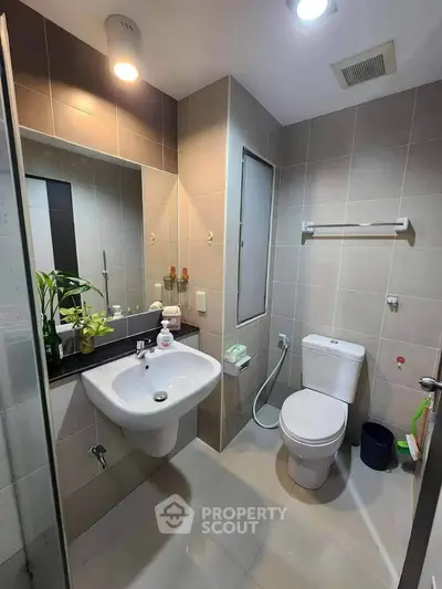 Modern bathroom with sleek fixtures and neutral tiles, featuring a spacious layout and contemporary design.