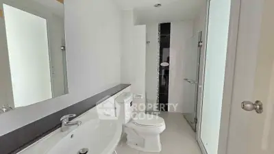 Modern bathroom with sleek fixtures and glass shower enclosure in a contemporary apartment.
