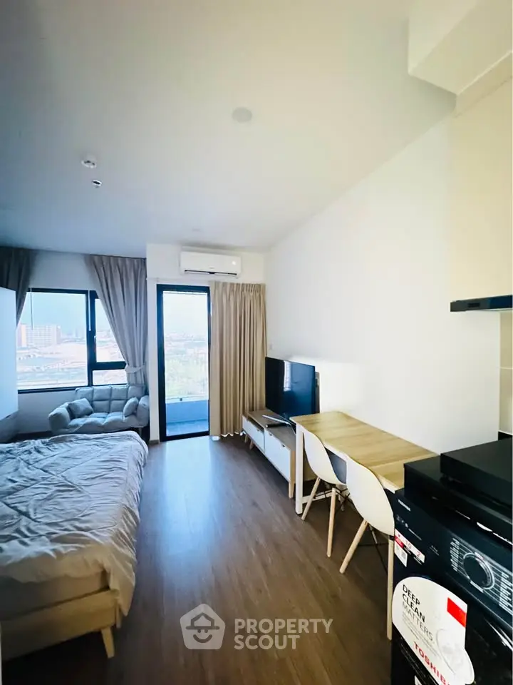 Modern studio apartment with balcony and city view, featuring cozy living area and stylish furnishings.