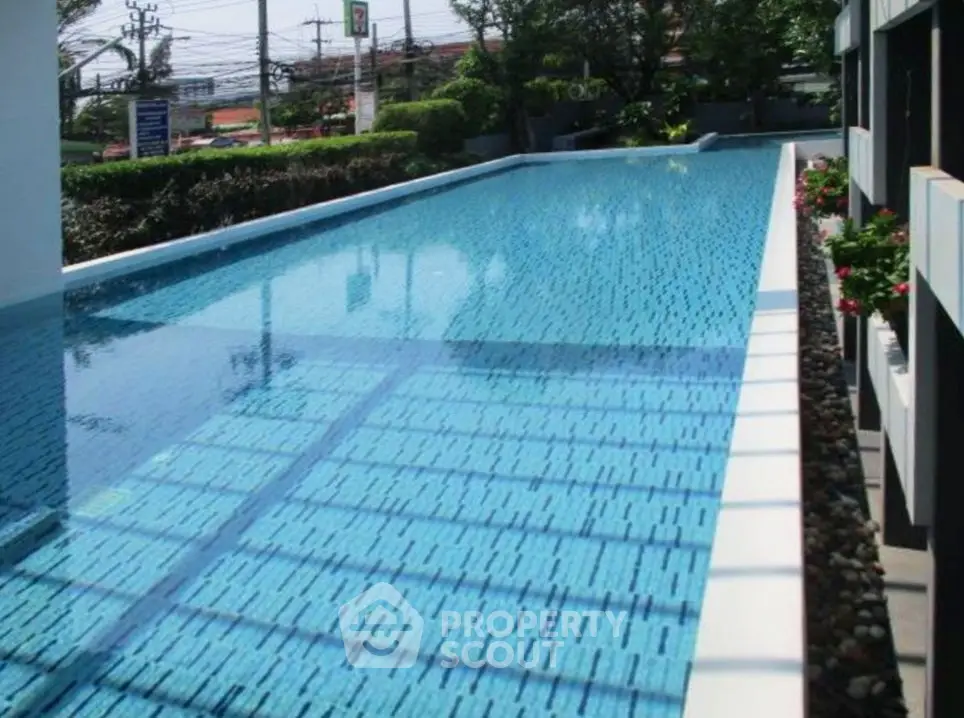 Luxurious outdoor swimming pool with clear blue water and lush greenery, perfect for relaxation and leisure.