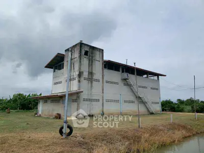 Rural two-story building with external staircase and open field view.