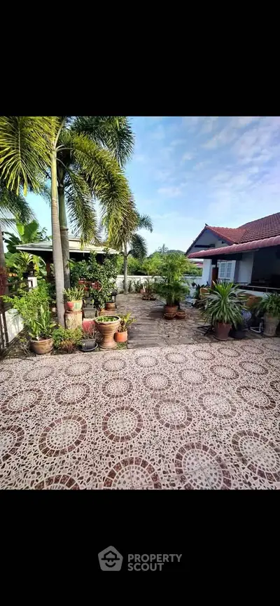Charming garden patio with lush greenery and tiled flooring in a serene residential setting.