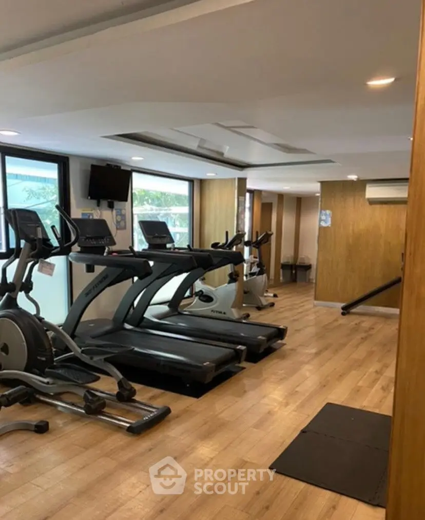 Modern gym with treadmills and wooden flooring in a residential building.