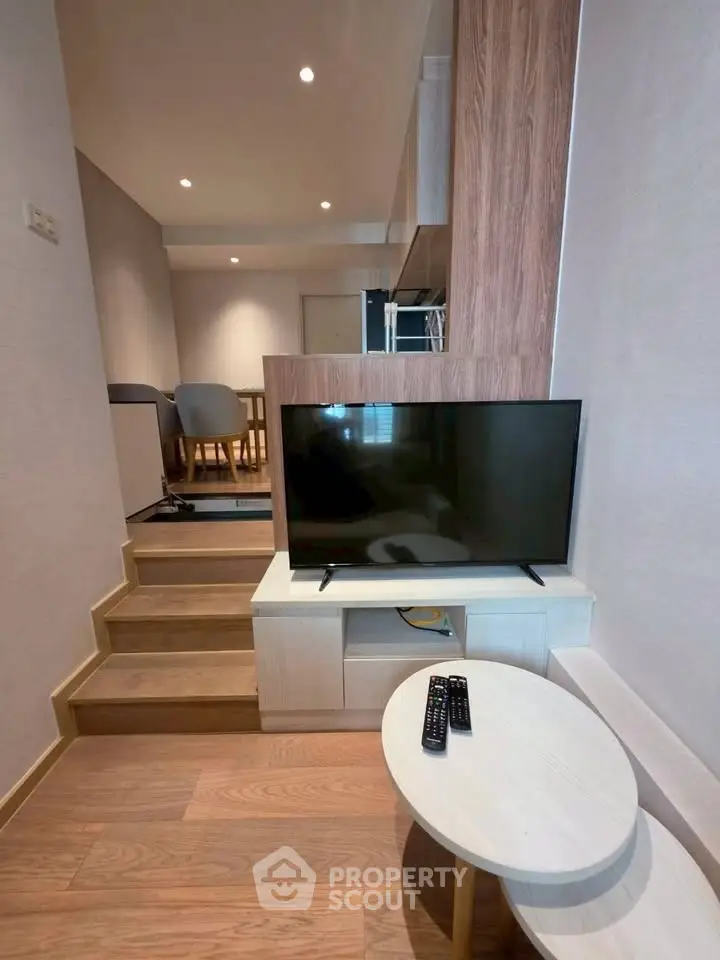 Modern living room with stylish wooden flooring and sleek TV setup in a cozy apartment.
