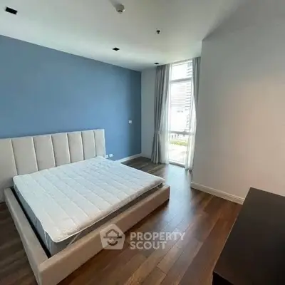 Spacious bedroom with modern design and large window offering natural light.