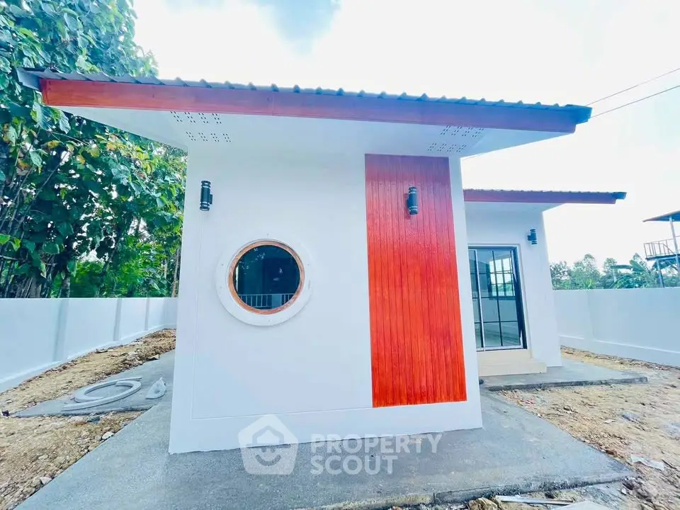 Modern minimalist small house with unique circular window and red accent wall