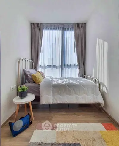 Cozy bedroom with modern decor and large window offering natural light.