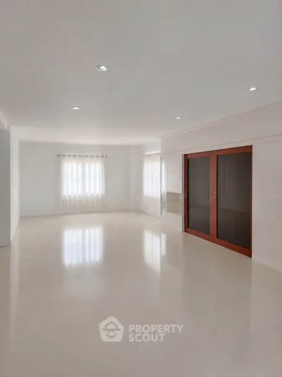 Spacious empty living room with large windows and sliding doors, perfect for customization.