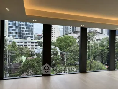 Spacious room with floor-to-ceiling windows offering a stunning cityscape view.