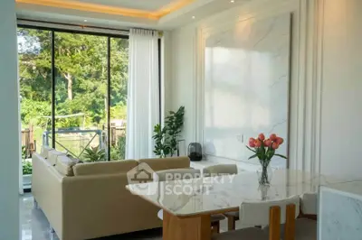 Elegant living room with large windows and garden view, featuring modern furniture and a marble dining table.