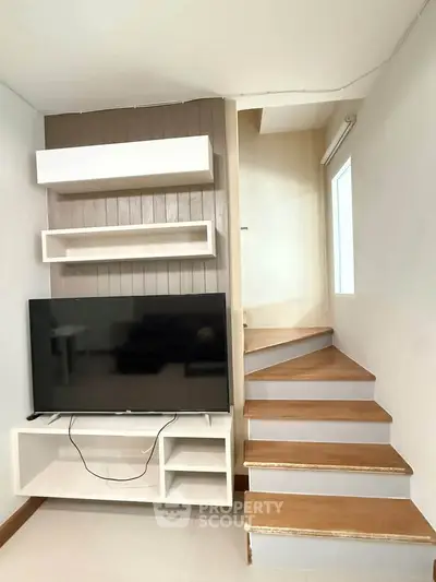 Modern living room with sleek TV unit and stylish staircase