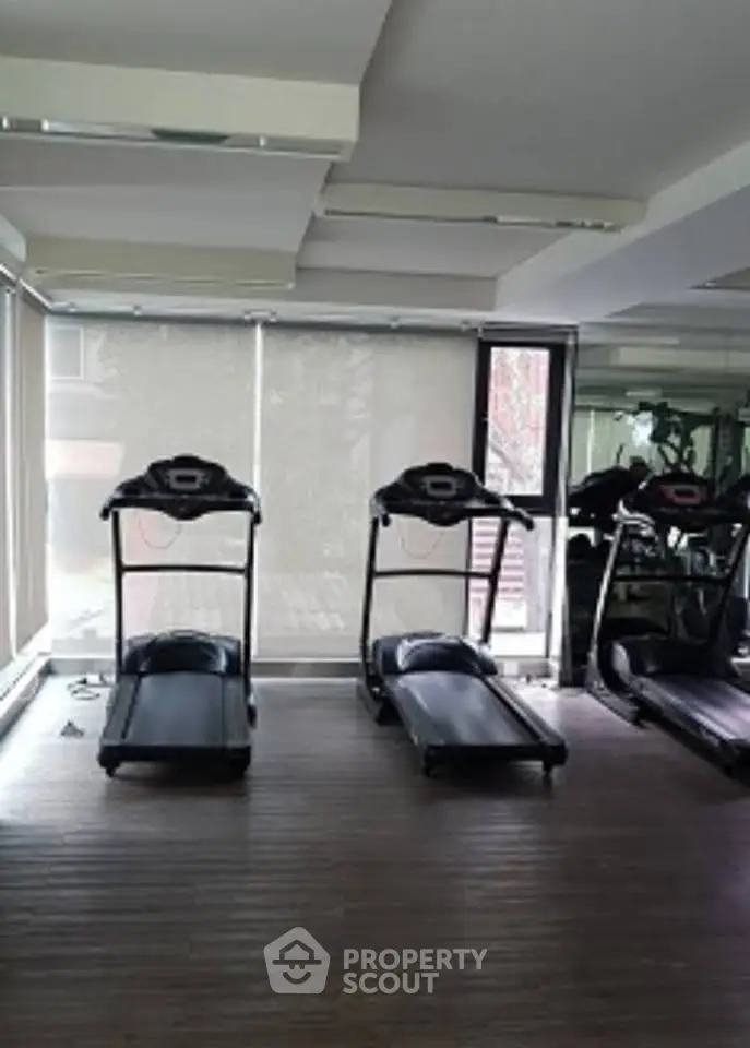 Modern gym with treadmills and large windows in a residential building.