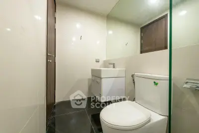 Modern bathroom with sleek fixtures and minimalist design, featuring a wall-mounted sink and toilet.