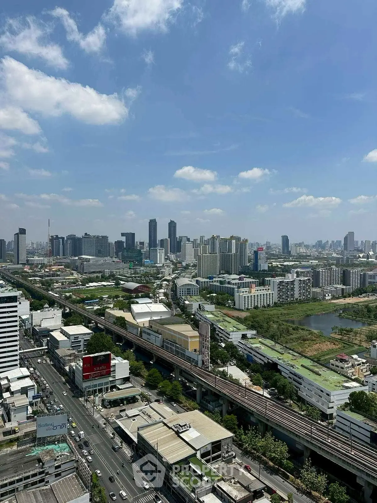 Stunning cityscape view with modern skyscrapers and lush greenery under a clear blue sky.