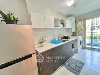 Modern kitchen with sleek cabinets, washing machine, and large window for natural light.
