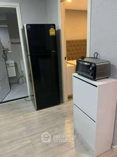 Modern apartment interior with sleek kitchen appliances and cozy bedroom view.