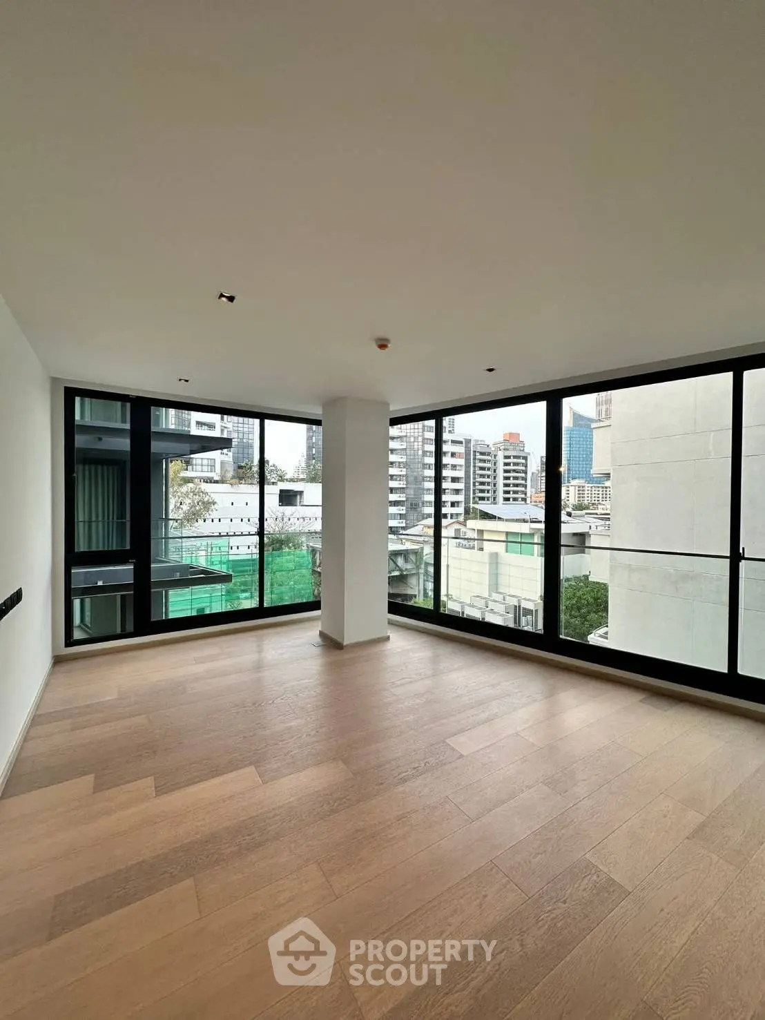 Spacious corner unit with floor-to-ceiling windows offering stunning city views in a modern apartment.