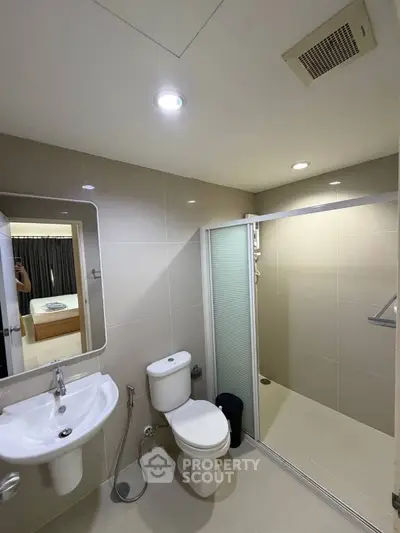 Modern bathroom with sleek fixtures and spacious shower in contemporary apartment.