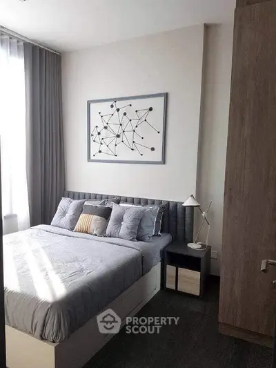 Modern bedroom with stylish decor and natural light, featuring a cozy bed and elegant artwork.