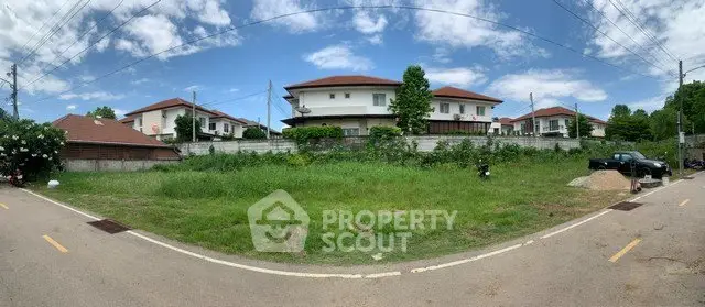 Spacious residential plot with lush greenery and modern houses in a serene neighborhood.