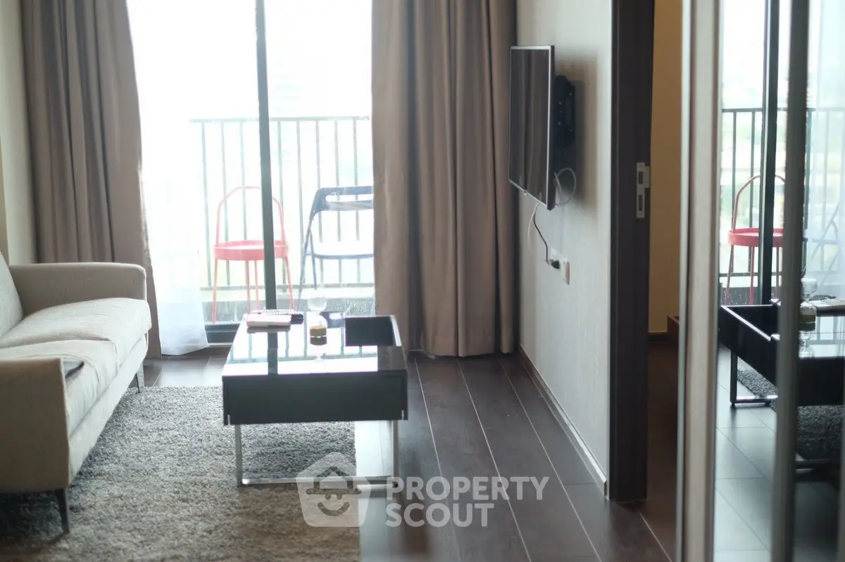 Modern living room with balcony view, sleek furniture, and natural light.