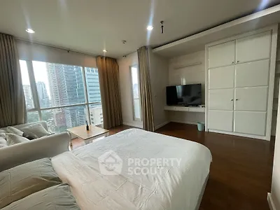 Spacious bedroom with city view, featuring modern decor and large windows for natural light.