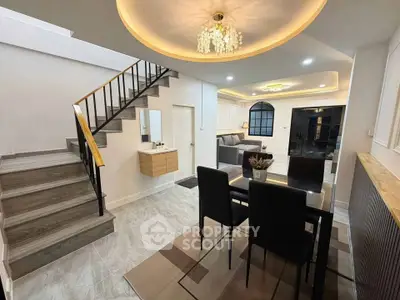 Modern living room with elegant staircase and dining area, featuring stylish lighting and contemporary decor.