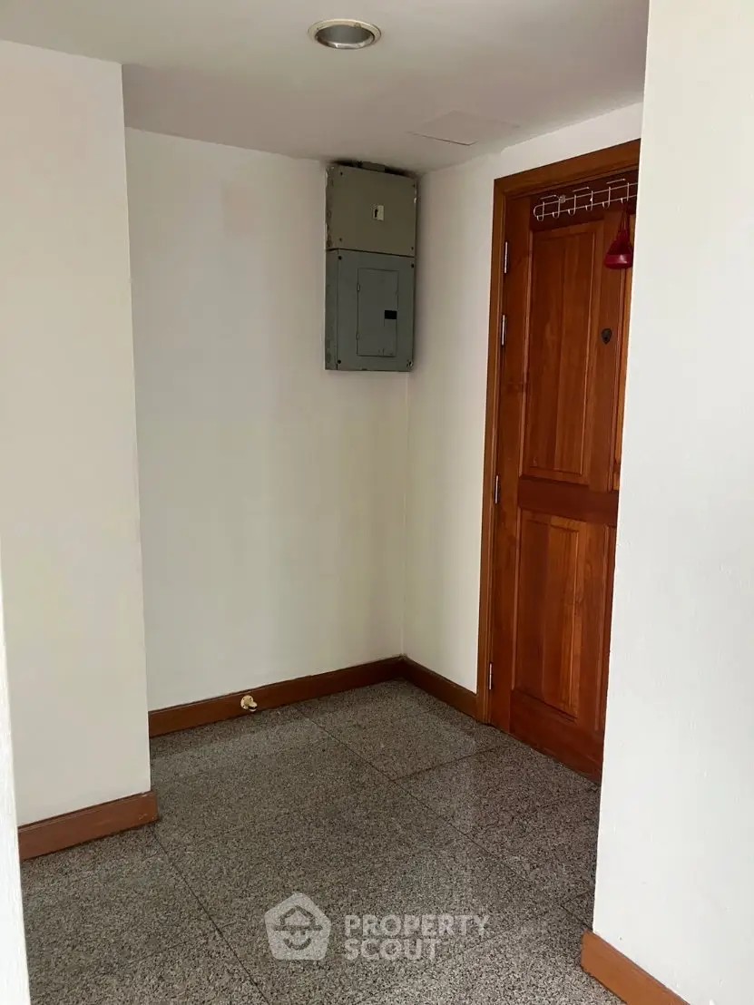Spacious apartment entrance with wooden door and electrical panel, ideal for modern living.