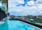 Stunning rooftop pool with panoramic city views under a vibrant blue sky.