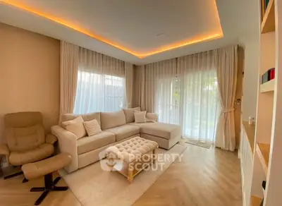 Elegant living room with cozy sectional sofa, ambient lighting, and large windows with sheer curtains.