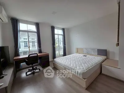 Spacious bedroom with modern furniture and large windows offering natural light.