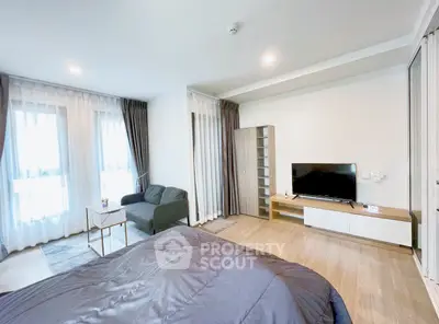 Spacious modern bedroom with cozy seating area and large windows