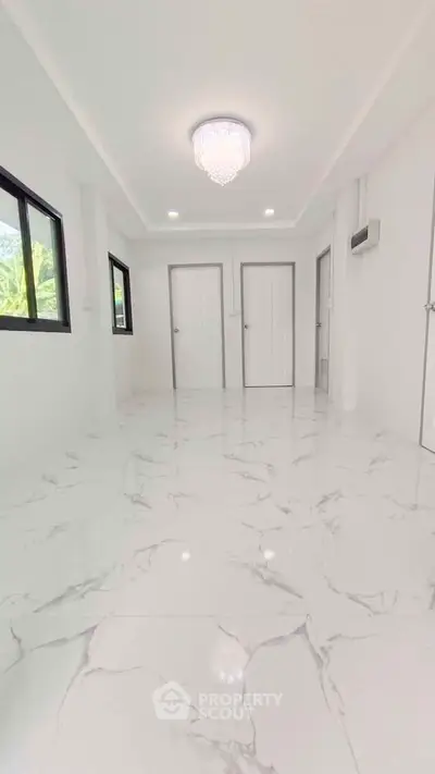 Spacious modern room with marble flooring and elegant chandelier lighting.