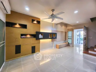 Spacious modern living room with built-in shelves and ceiling fan