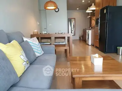 Charming open-plan living room with cozy sofa and modern kitchen appliances.