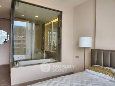 Luxurious bedroom with glass-walled ensuite bathroom featuring a modern bathtub and elegant decor.