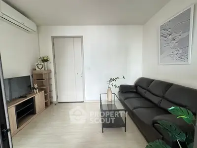 Modern living room with sleek black sofa, minimalist decor, and wall-mounted air conditioner.