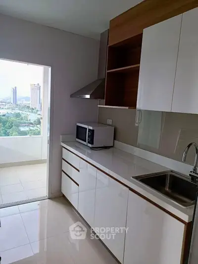 Modern kitchen with sleek cabinetry and city view from balcony