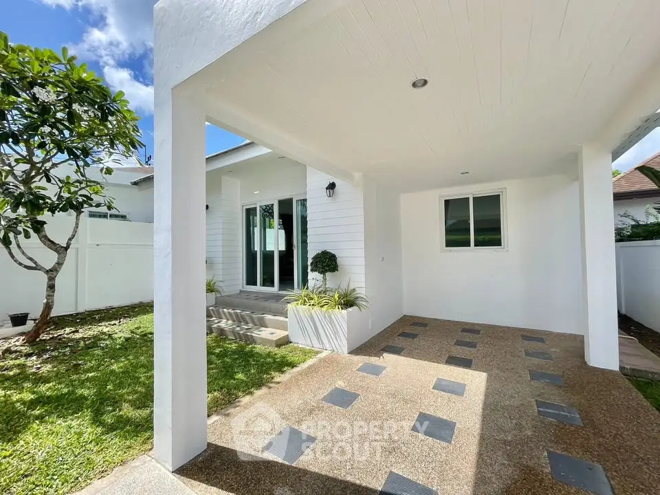 Charming modern home entrance with covered patio and lush greenery