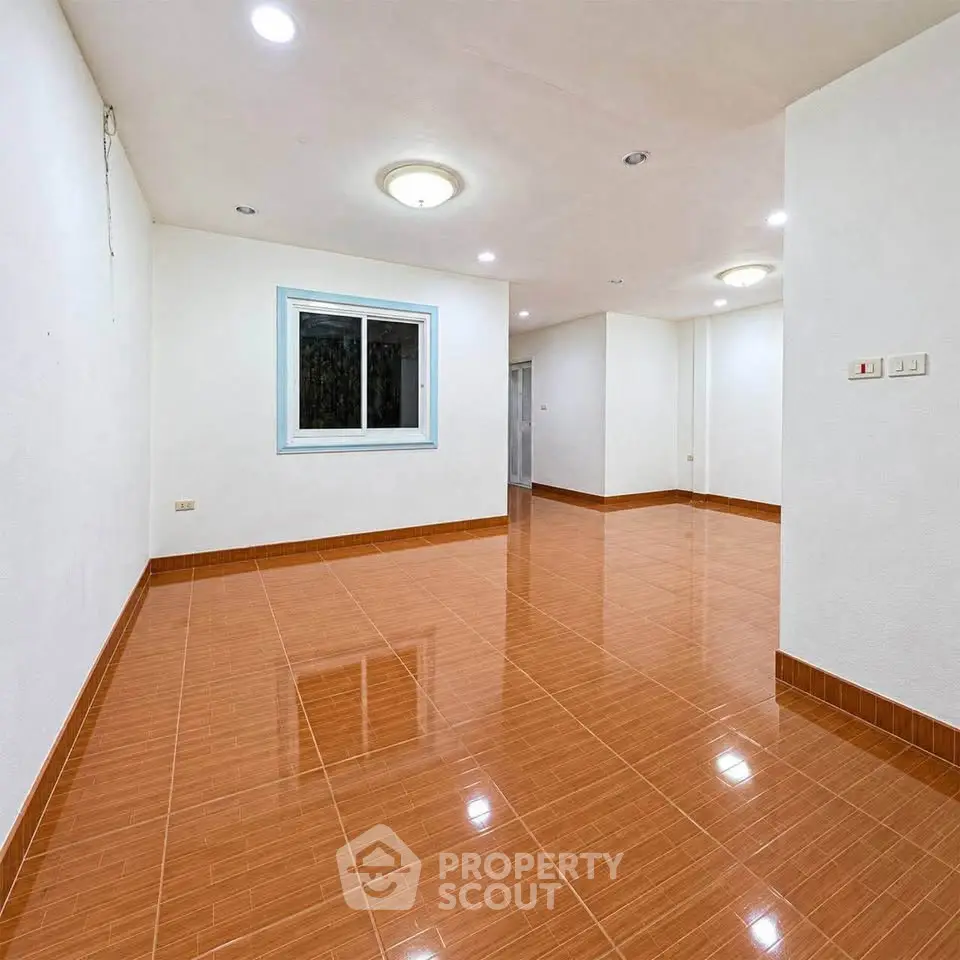 Spacious empty room with glossy tiled flooring and bright lighting, ideal for customization.