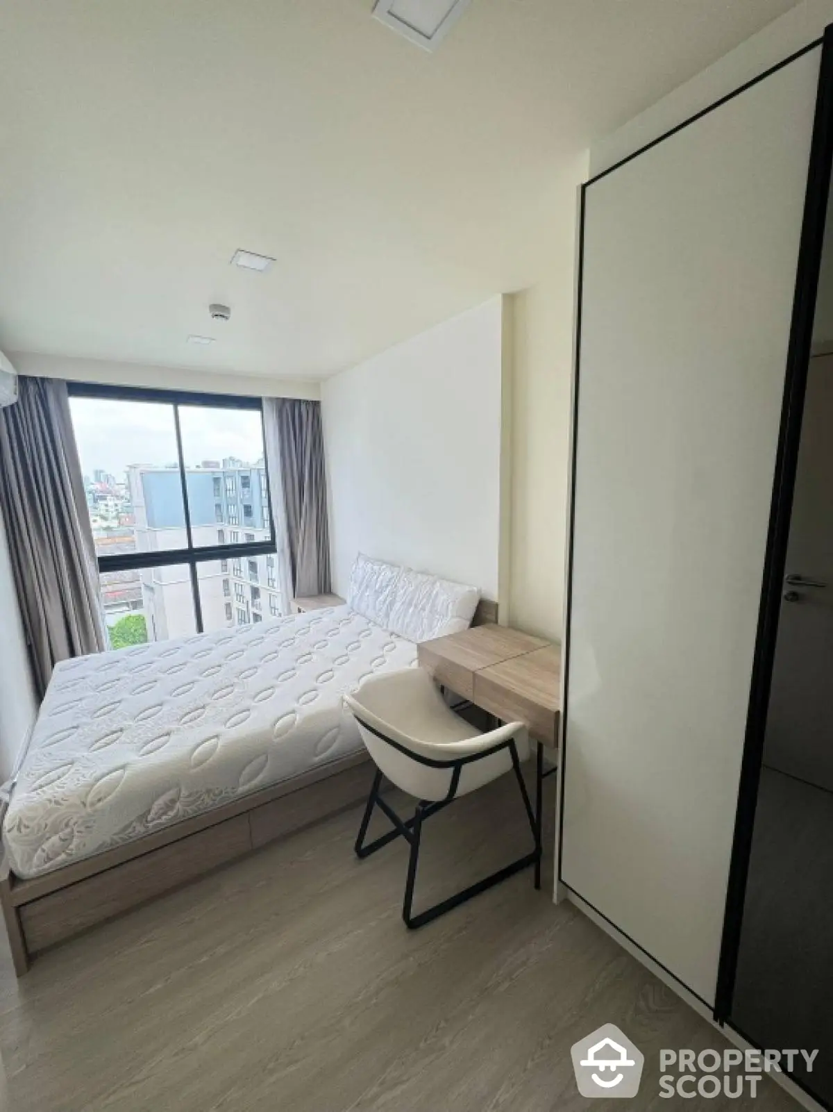 Modern bedroom with city view, featuring sleek furniture and large window for natural light.