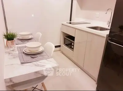 Modern compact kitchen with sleek design and dining area, featuring built-in appliances and elegant decor.