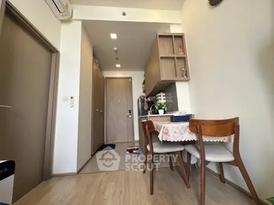 Cozy dining area in modern apartment with wooden furniture and open kitchen layout.