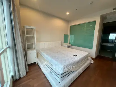 Spacious bedroom with large windows and modern furnishings in a stylish apartment.