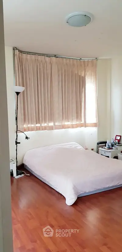 Cozy bedroom with wooden flooring and soft lighting, perfect for relaxation.
