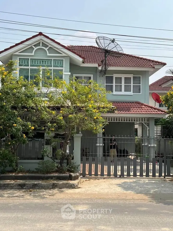 Charming two-story house with red-tiled roof and lush garden, perfect for family living.