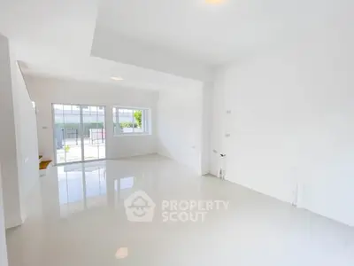 Spacious and bright empty living room with large windows and glossy floors.