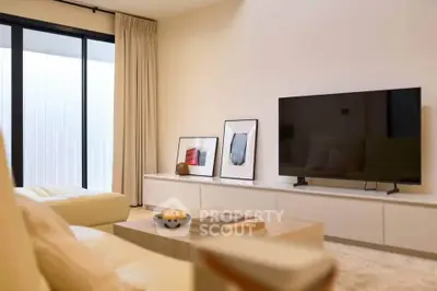 Modern living room with sleek decor and large TV, featuring minimalist design and natural light.