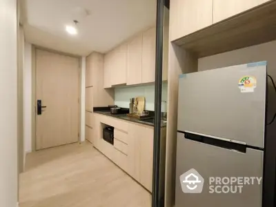 Modern kitchen with sleek cabinetry and stainless steel refrigerator in a stylish apartment.