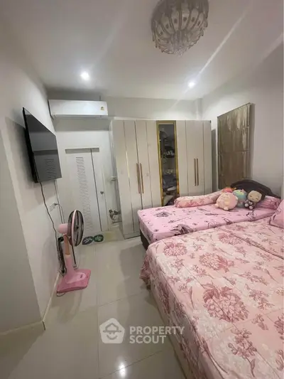 Cozy bedroom with twin beds, wall-mounted TV, and ample wardrobe space.